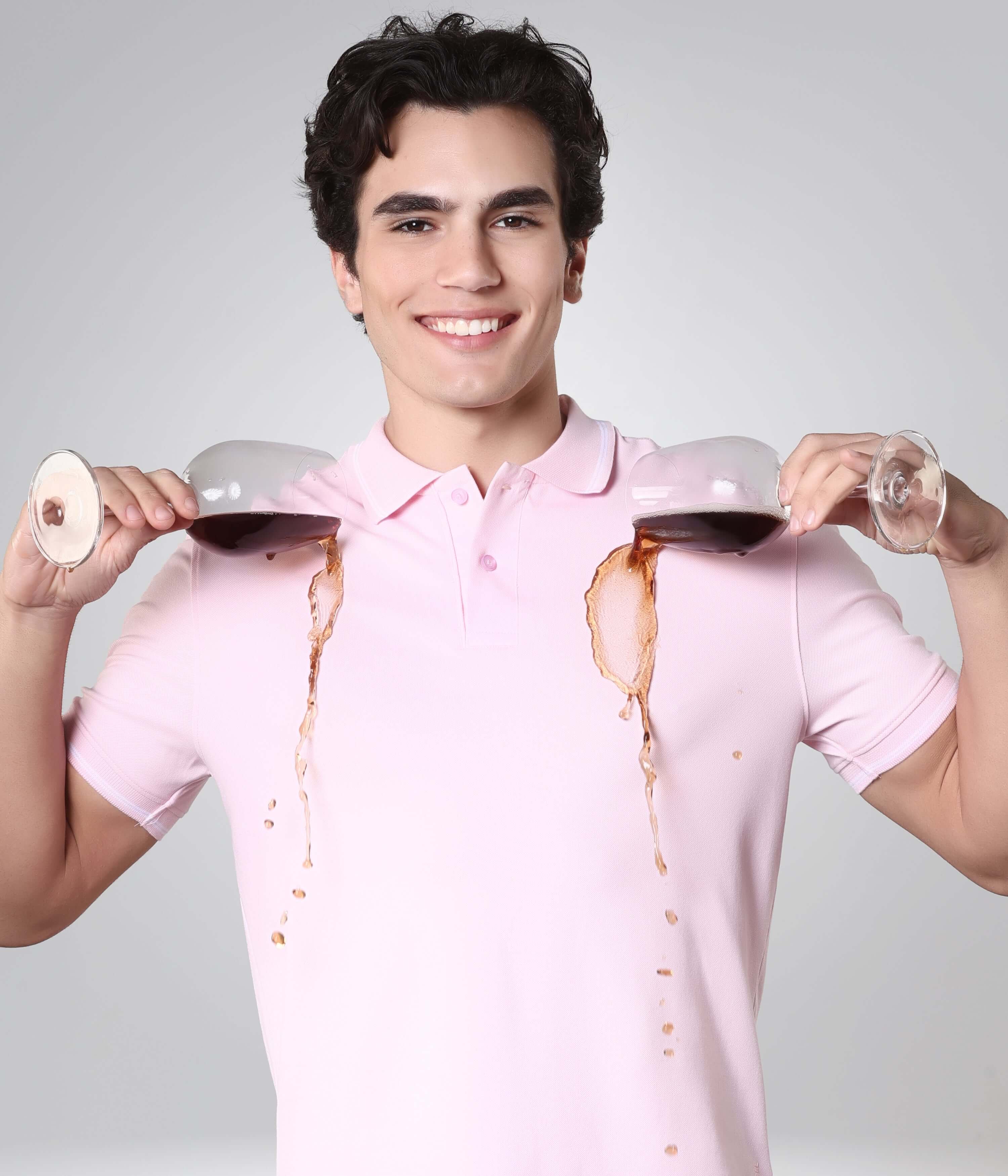 Man wearing pink Turms Polo T-shirt with wine spilled showing anti-stain protection, premium cotton, tailored fit, anti-odor, intelligent apparel