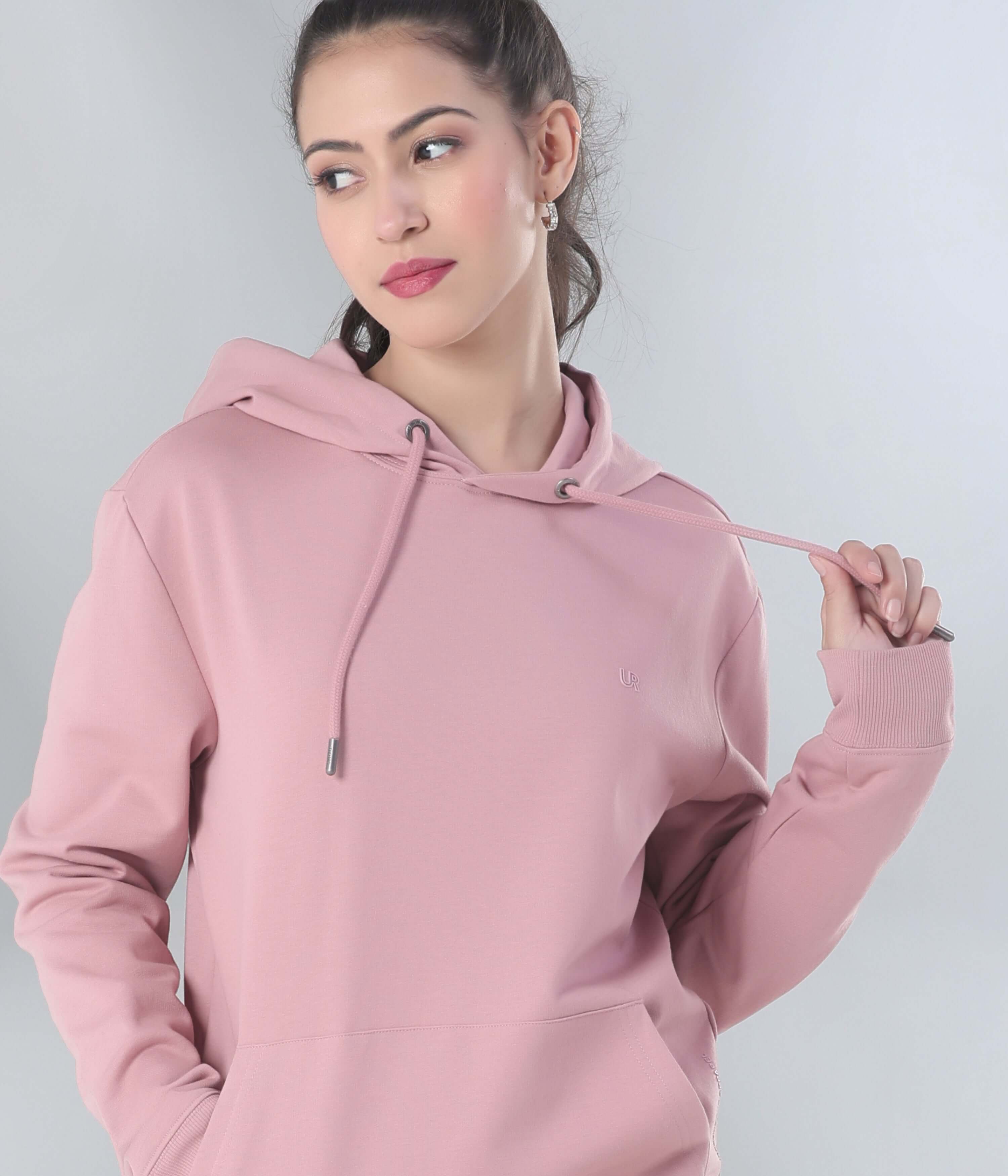 Stylish woman wearing a pink hooded sweatshirt from Turms, showcasing comfort and innovative design for everyday wear.