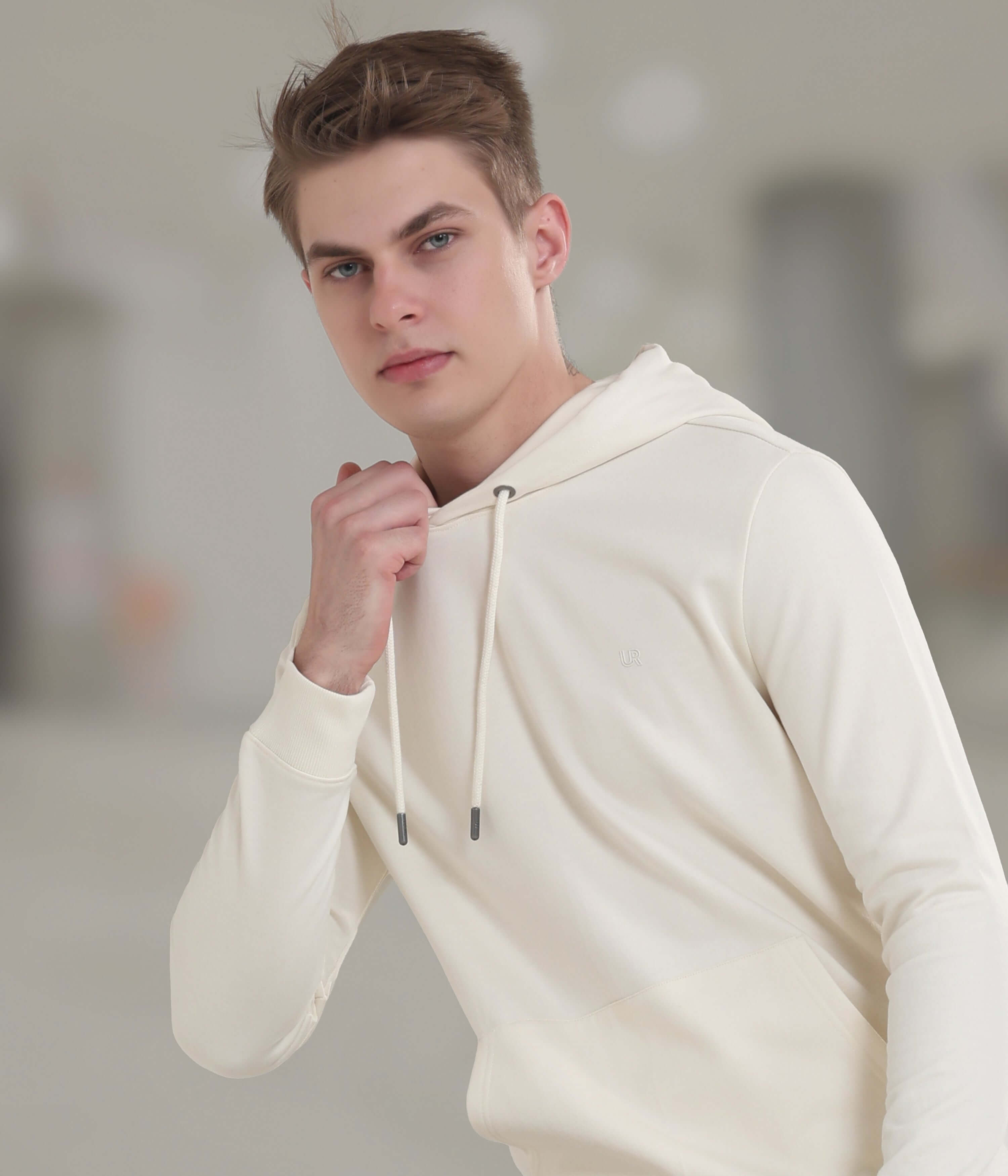 Stylish young man wearing a cream-colored water-proof hooded sweatshirt for comfortable everyday wear.