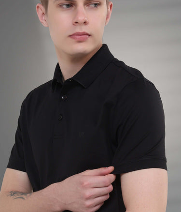 Young man wearing a black tailored fit polo t-shirt, showcasing waterproof and stain-proof features.