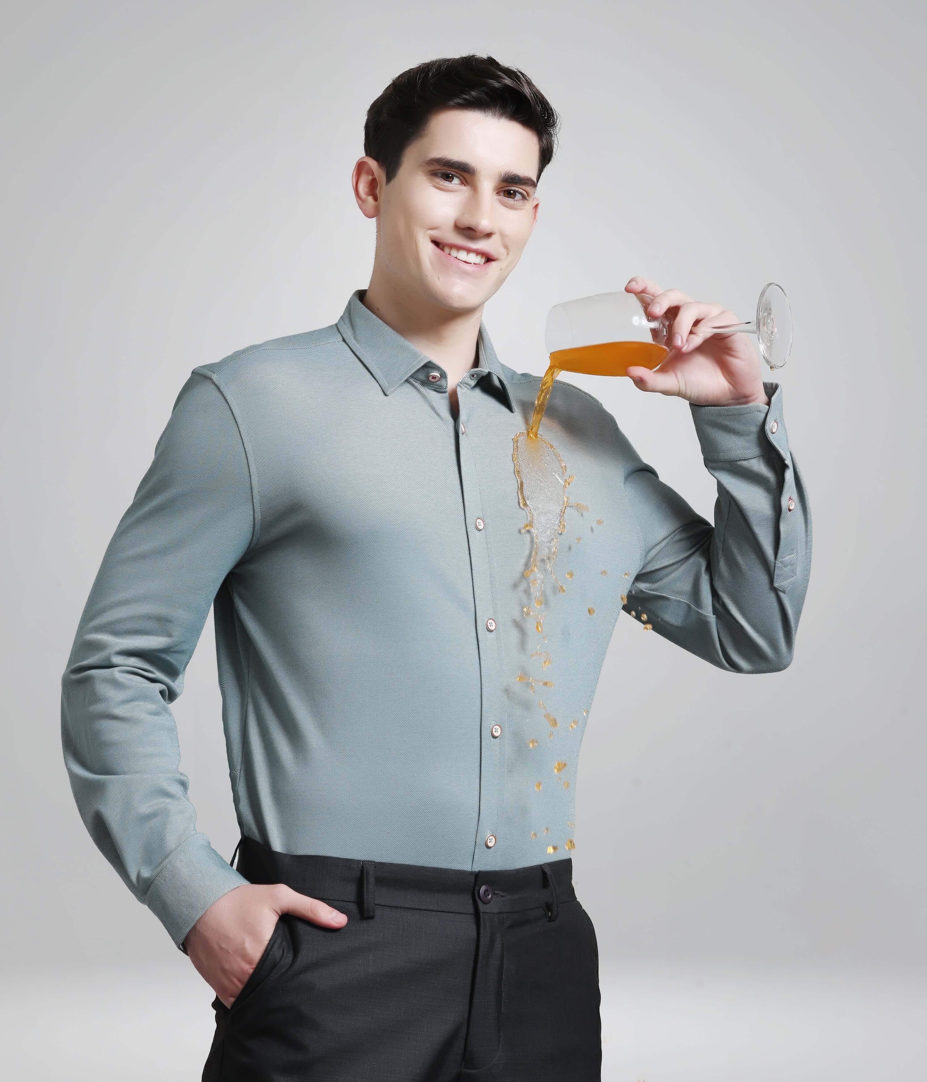 Man wearing jadeite green anti-stain knitted shirt shows liquid resistance feature of premium men's shirt.