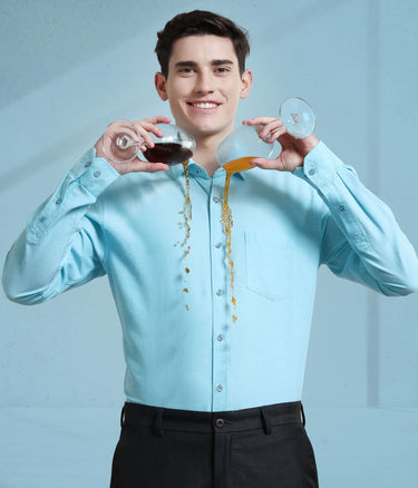 Man in turquoise Oxford shirt showcasing anti-stain, anti-odour features with spilled drinks, highlighting Turms intelligent apparel.