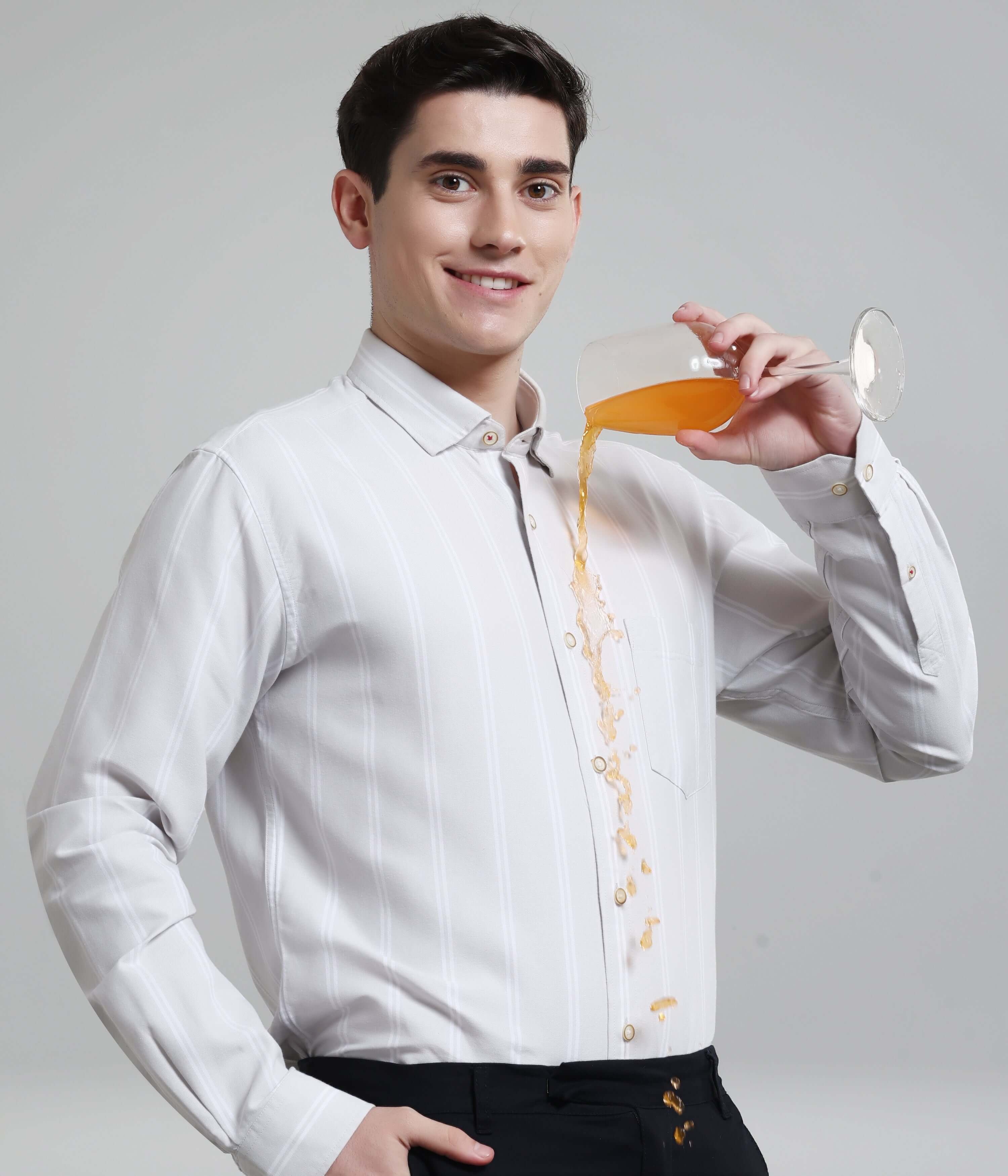 Man wearing Stormveil Grey anti-stain Oxford Turms stripe shirt pouring juice, showcasing premium menswear functionality.