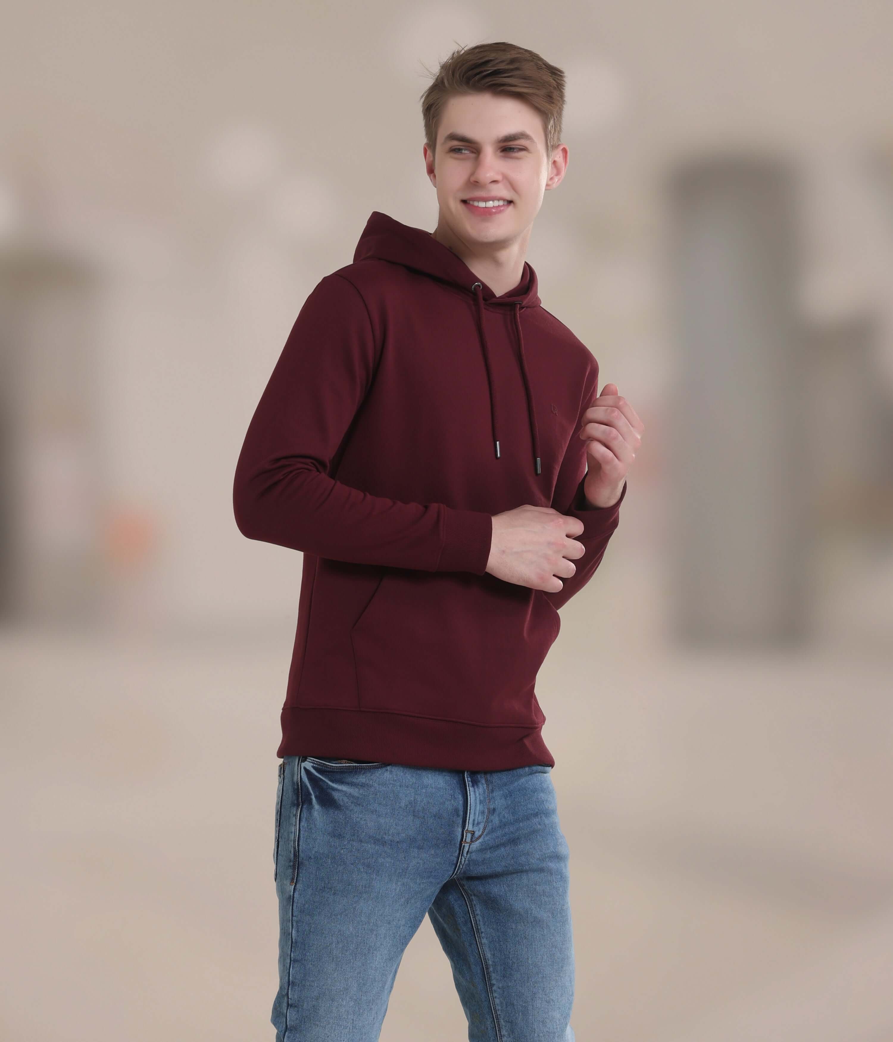 Young man in burgundy hooded sweatshirt, showcasing stylish and comfortable design for everyday wear.