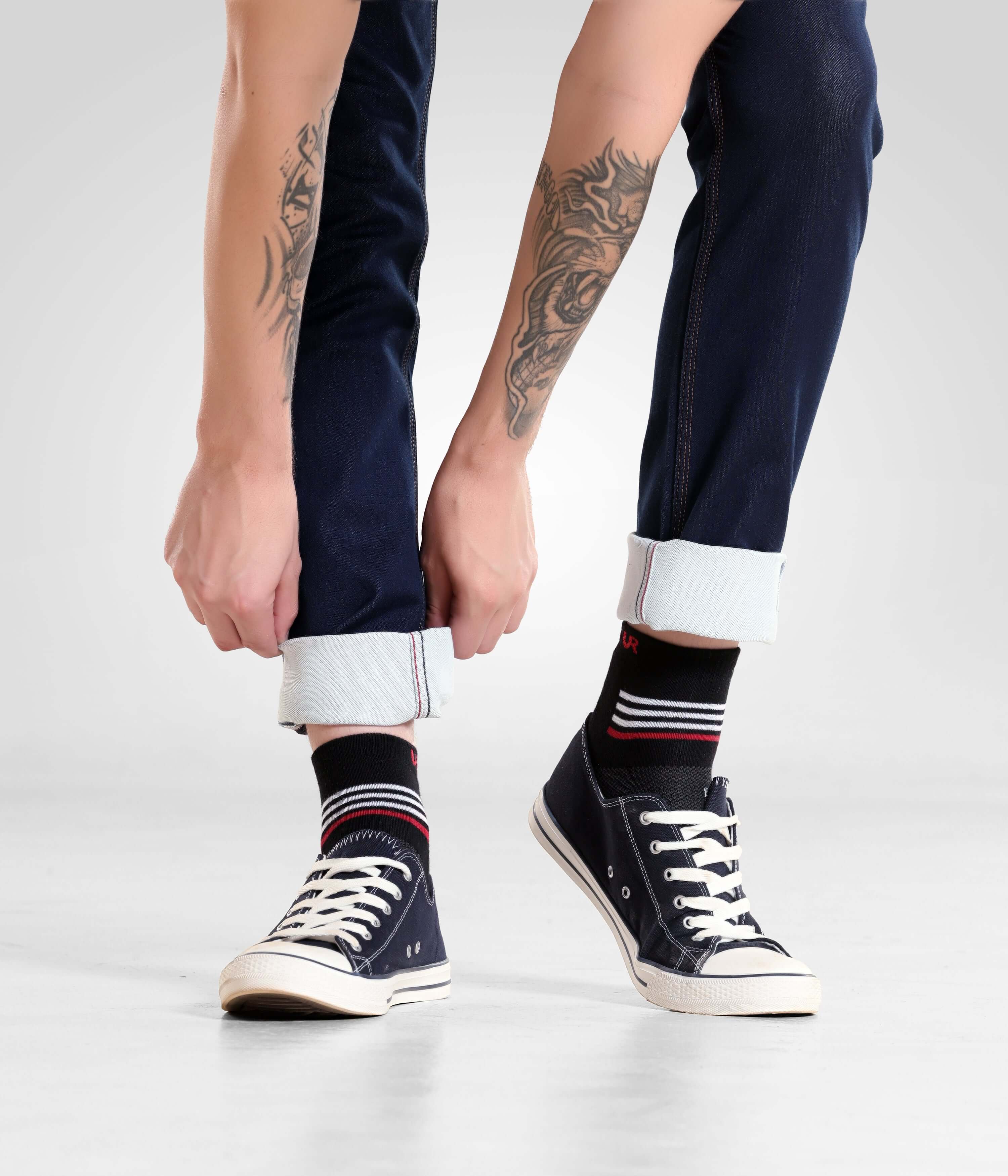 Man wearing Indigo Trotter high-performance denim pants from Turms Intelligent Apparel with rolled cuffs and sneakers, showcasing stylish menswear.