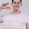 Man in lavender polo shirt demonstrating the anti-stain feature by pouring juice without worry.