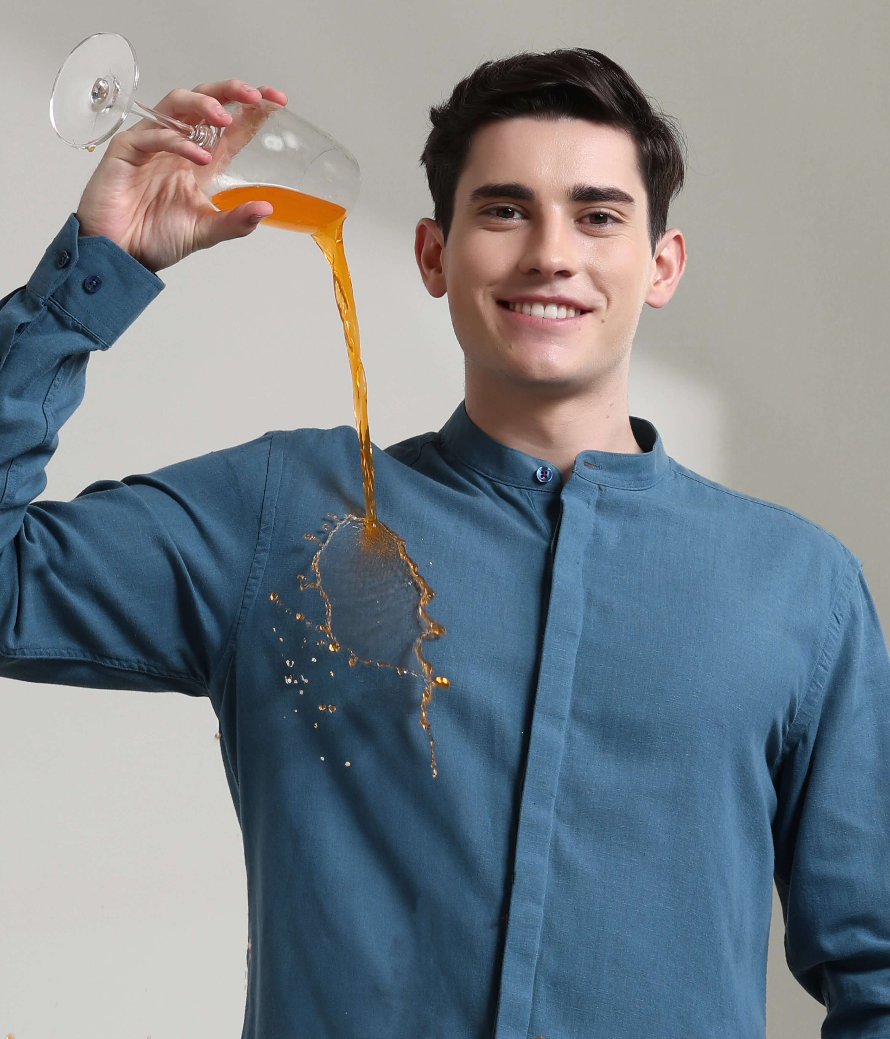 Man wearing Onyx Teal Turms shirt with mandarin collar, demonstrating anti-stain feature by pouring liquid on linen fabric.