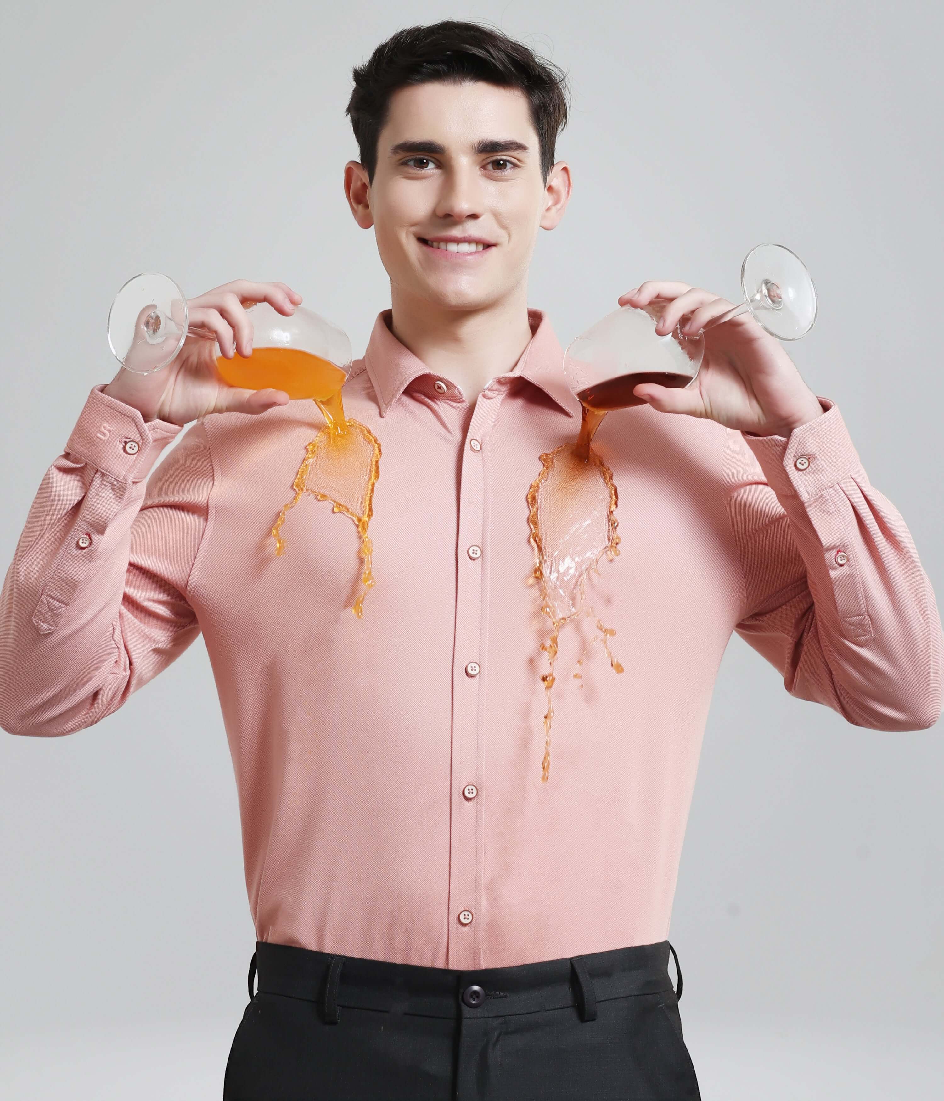 Man wearing pink anti-stain knitted shirt with liquid pouring on it showing durability and functionality.