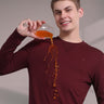 Man in maroon sweatshirt demonstrating waterproof feature while pouring drink without stains, showcasing anti-odor technology.