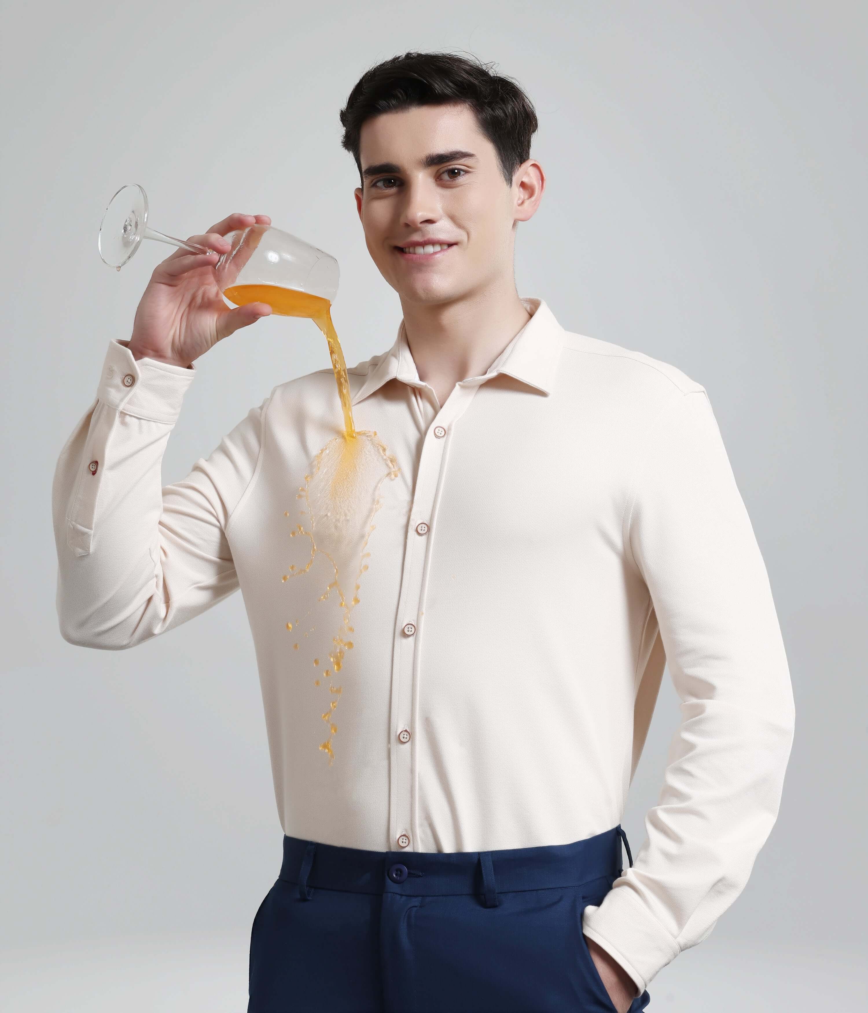 Man in Dusky Beige Knitted Shirt demonstrating anti-stain feature with spilled drink, showcasing premium menswear.