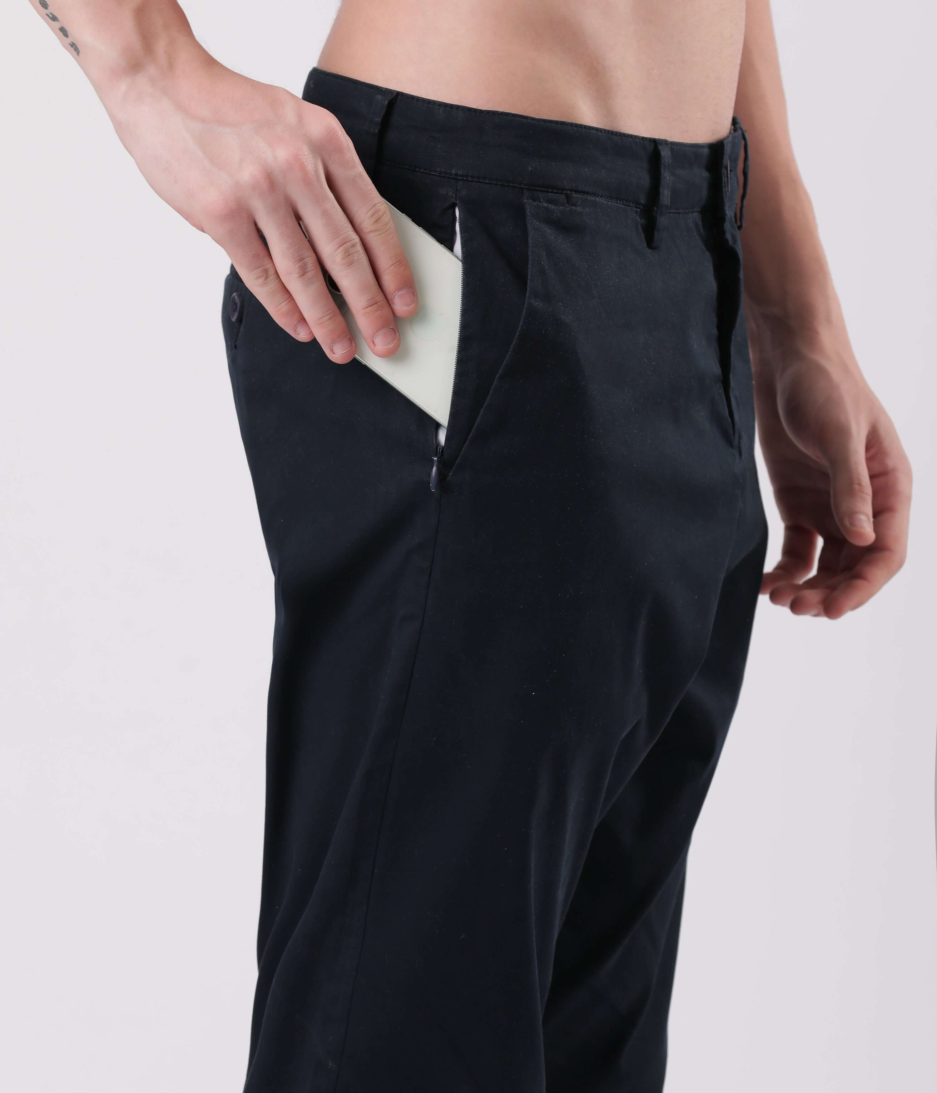 Man placing a phone in the pocket of Turms Blue Eyed Chino pants showcasing style and functionality.