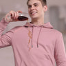 Stylish man in pink musing hoodie showcasing waterproof, stain-proof functionality while enjoying a drink.