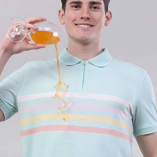 Man wearing a blue origami polo shirt, demonstrating its anti-stain feature with a drink, highlighting its stylish design.