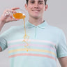 Man wearing a blue origami polo shirt, demonstrating its anti-stain feature with a drink, highlighting its stylish design.
