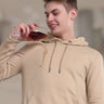 Man in a camel-colored hooded sweatshirt enjoying a drink, showcasing stain-proof and durable fabric features.
