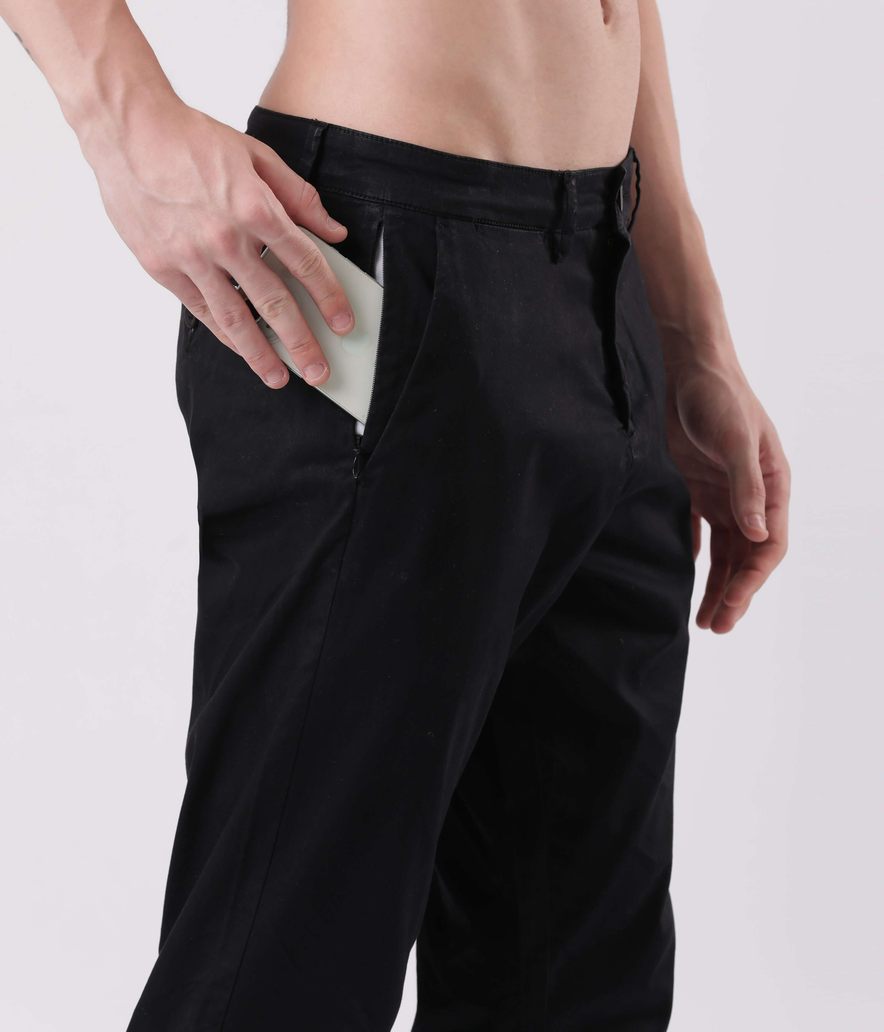 Man wearing Turms Black Sea Chino, placing a phone in the side pocket for convenient storage.