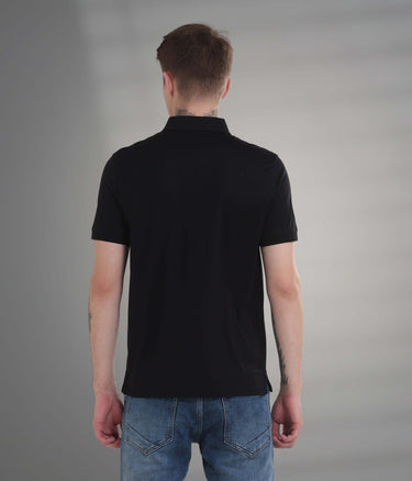 Back view of a man wearing a black stain-proof polo shirt, showcasing a tailored fit and premium cotton blend.
