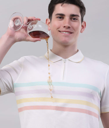 Man wearing a striped vanilla cream polo shirt, pouring liquid from a glass with a zipper detail.