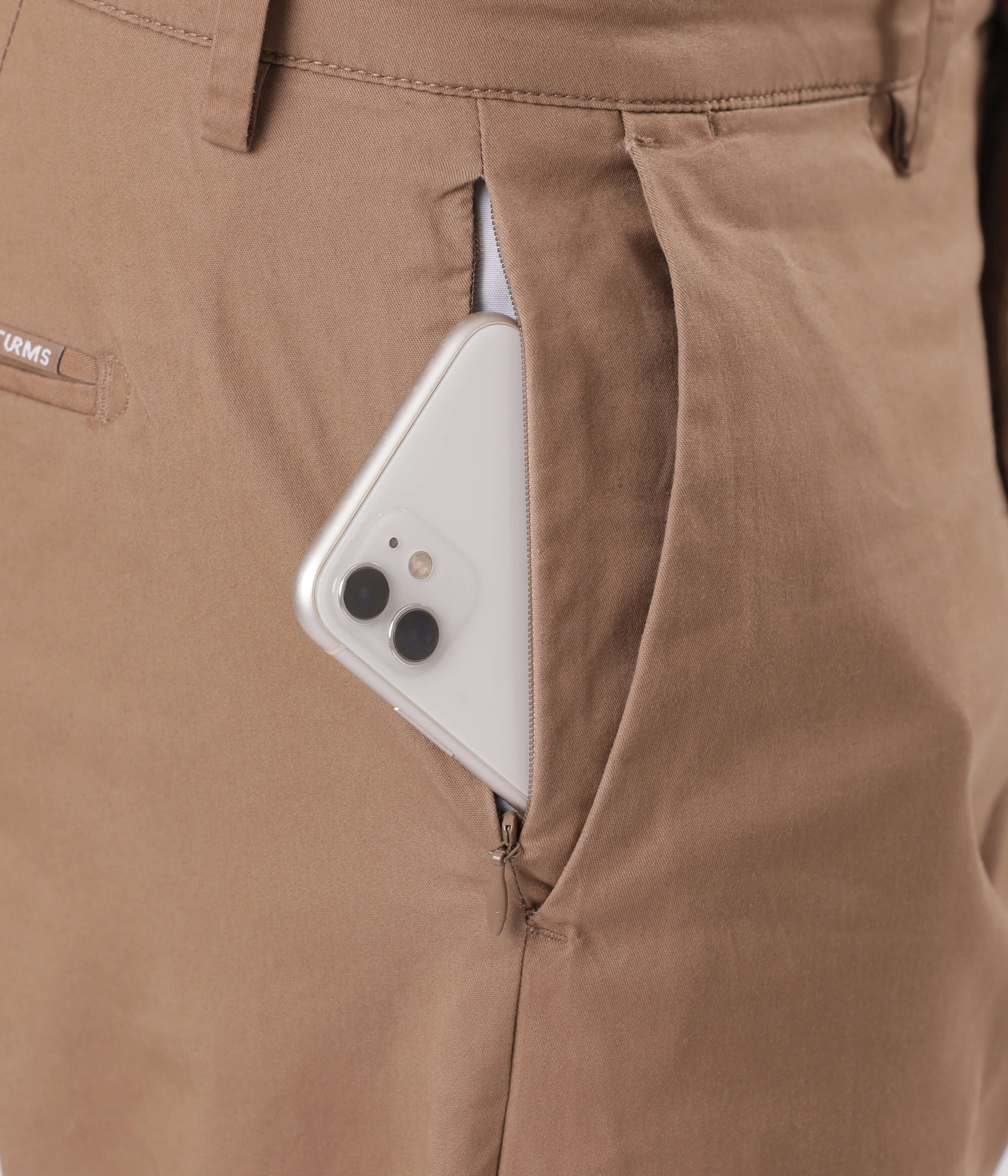 Close-up of Turms Chino pocket with smartphone, showcasing the stylish functionality of Dessert Mirage.