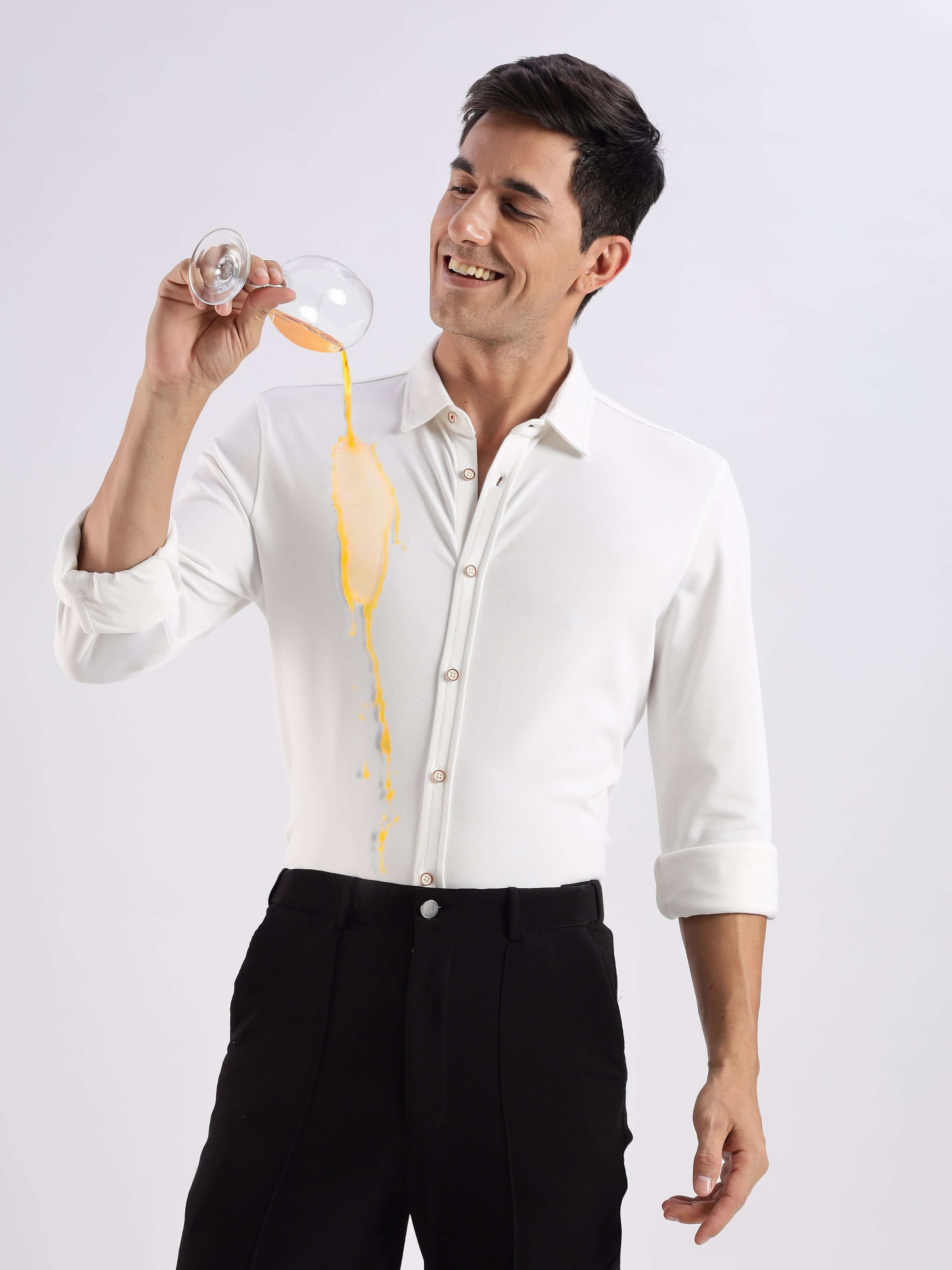 Man in a White Willow knitted shirt pouring juice, showcasing its anti-stain and premium quality features.