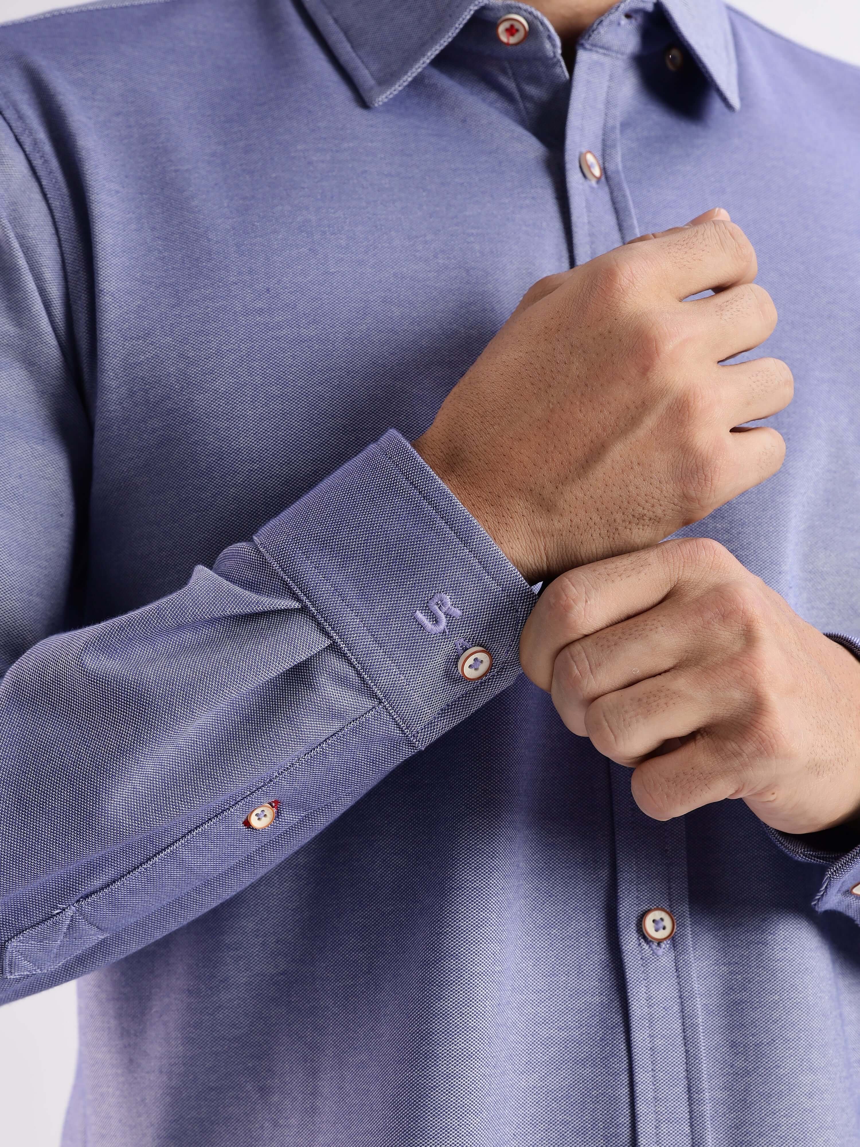 Close-up of a man in a blue knitted shirt showcasing 8-way stretch, anti-odour, and anti-stain features from Turms.
