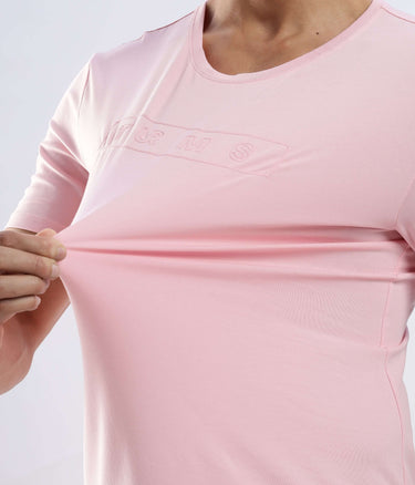 Close-up of a person stretching a Quartz Pink cotton tshirt, showcasing its stretchable and comfortable design.