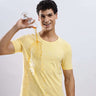 Aura Yellow cotton t-shirt, stretchable and waterproof, showcased by a smiling man spilling liquid from a glass.