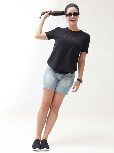 Woman wearing black Turms T-shirt and denim shorts, showcasing anti-stain, anti-odour, stretchable intelligent apparel.