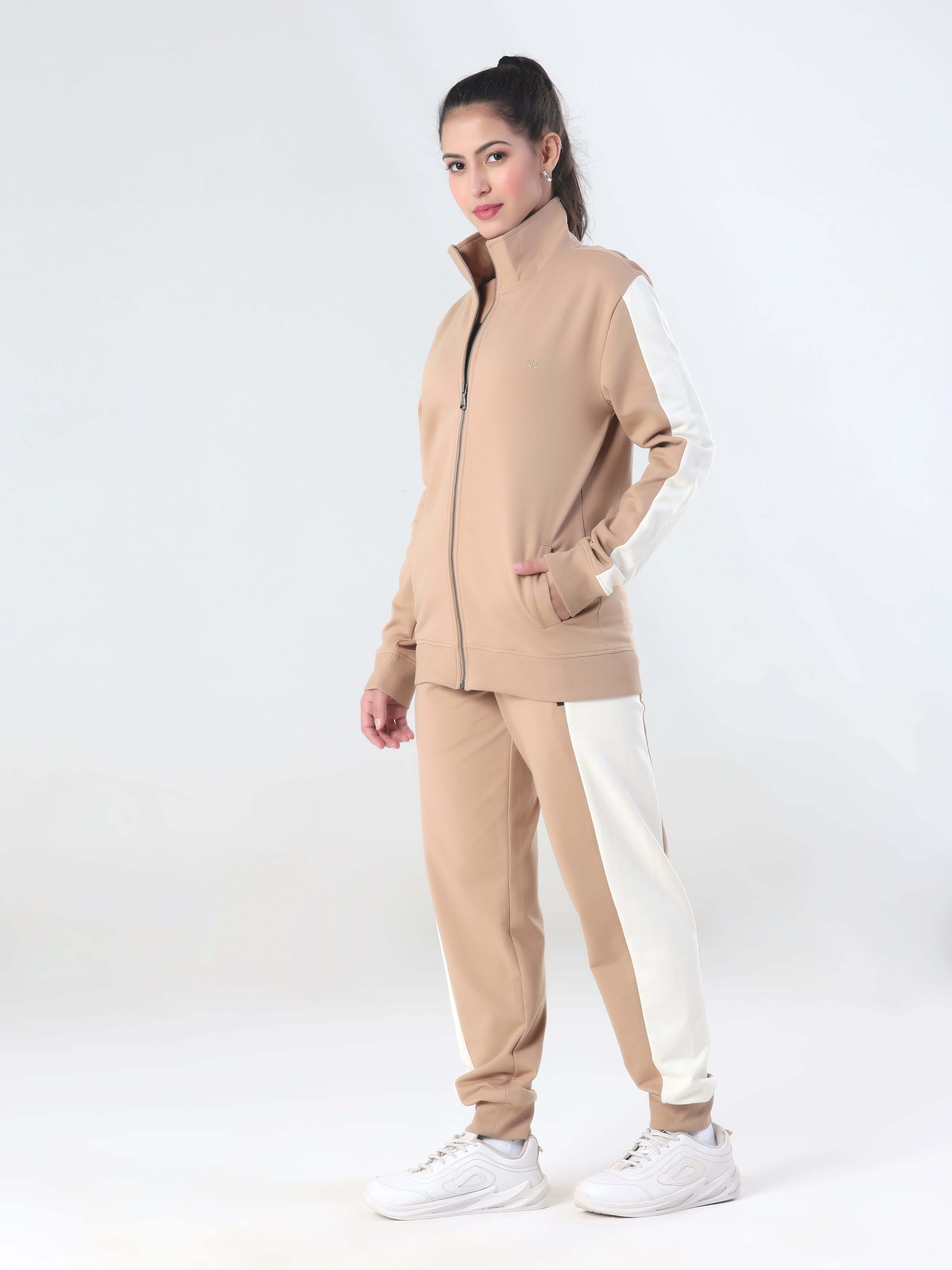 A woman modeling the Sandy Heaven Turms Intelligent Cord Set, featuring a sporty jacket and joggers in beige with white accents.