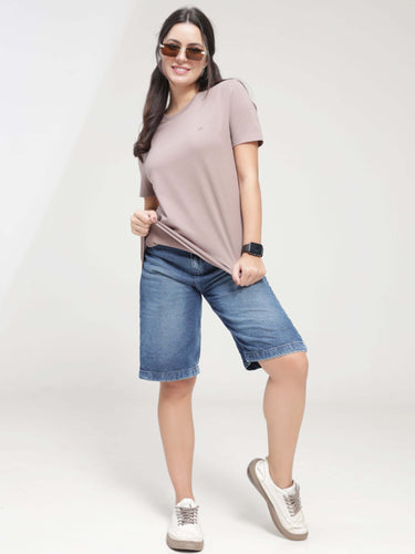 Woman wearing Dusky Maroon Turms T-shirt, tailored fit, round neck, paired with denim shorts and white sneakers, showcasing anti-stain, anti-odor, and stretchable intelligent apparel.