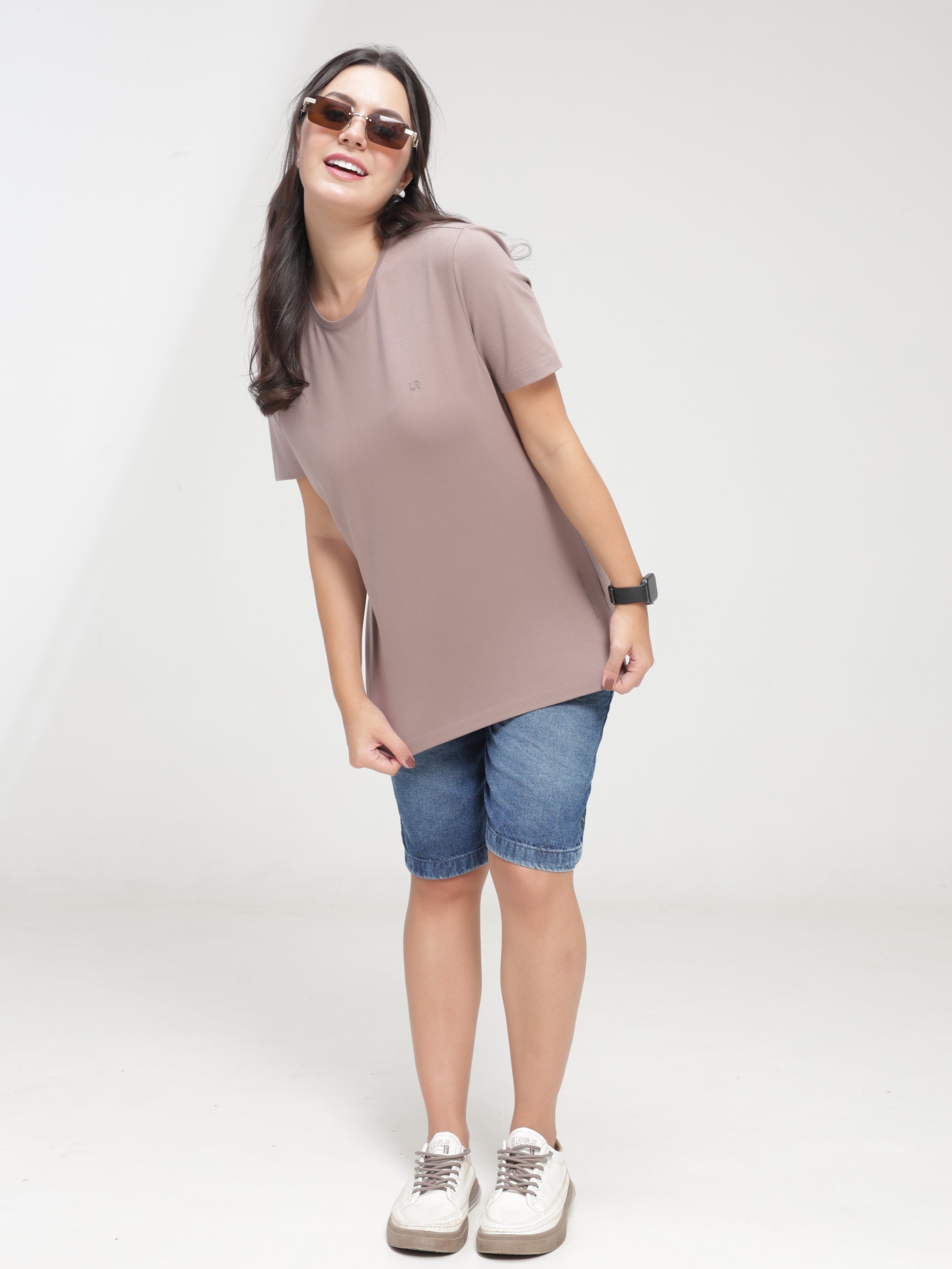 Woman wearing Dusky Maroon Turms T-shirt, anti-stain, anti-odor, stretchable, tailored fit, crew neckline, paired with denim shorts.