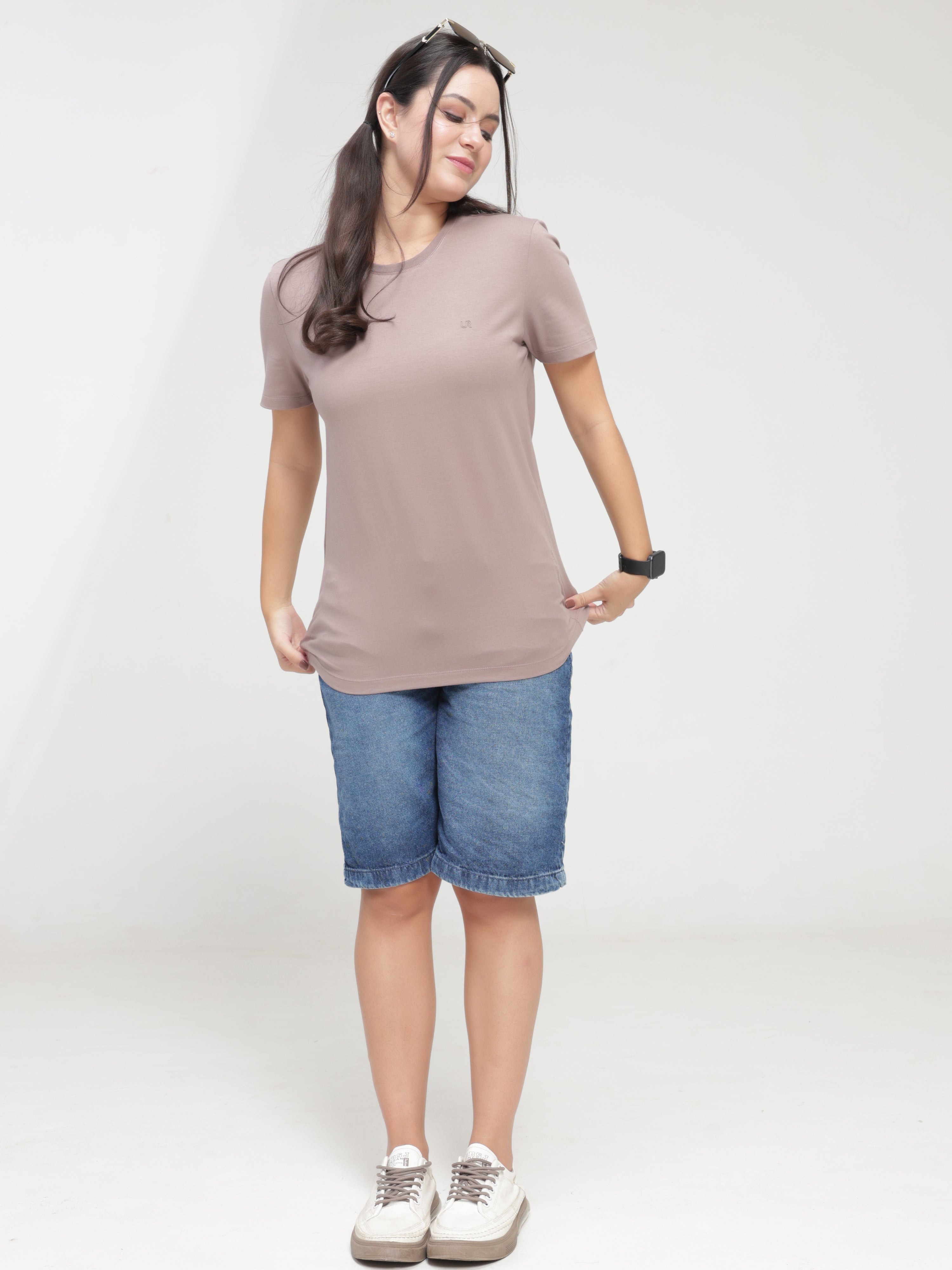 Woman wearing Dusky Maroon Turms T-shirt, anti-stain, anti-odor, stretchable, tailored fit, and intelligent apparel, paired with denim shorts.