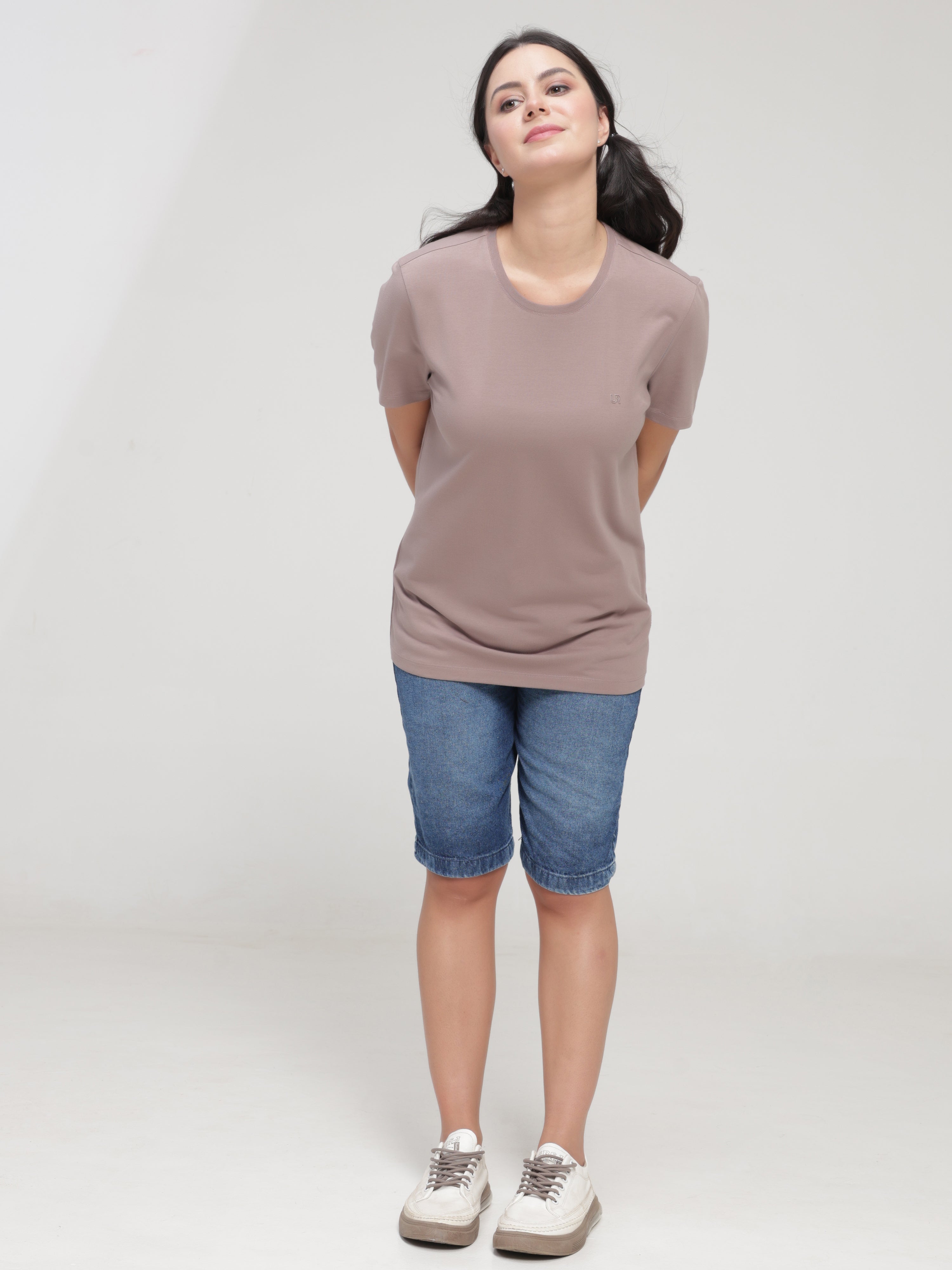 Woman wearing a Dusky Maroon Turms T-shirt, stain-proof, anti-odor, and stretchable, paired with denim shorts.