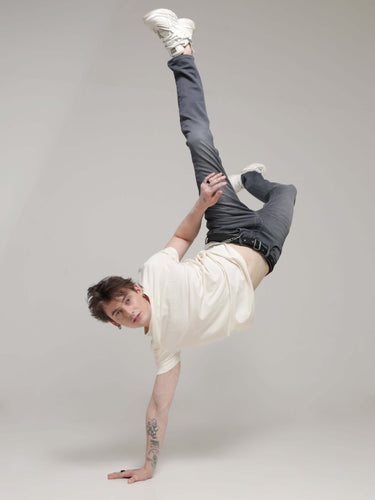 Man performing a handstand wearing a Soft Peach Turms t-shirt, showcasing its stretchable and anti-stain, anti-odour intelligent fabric.