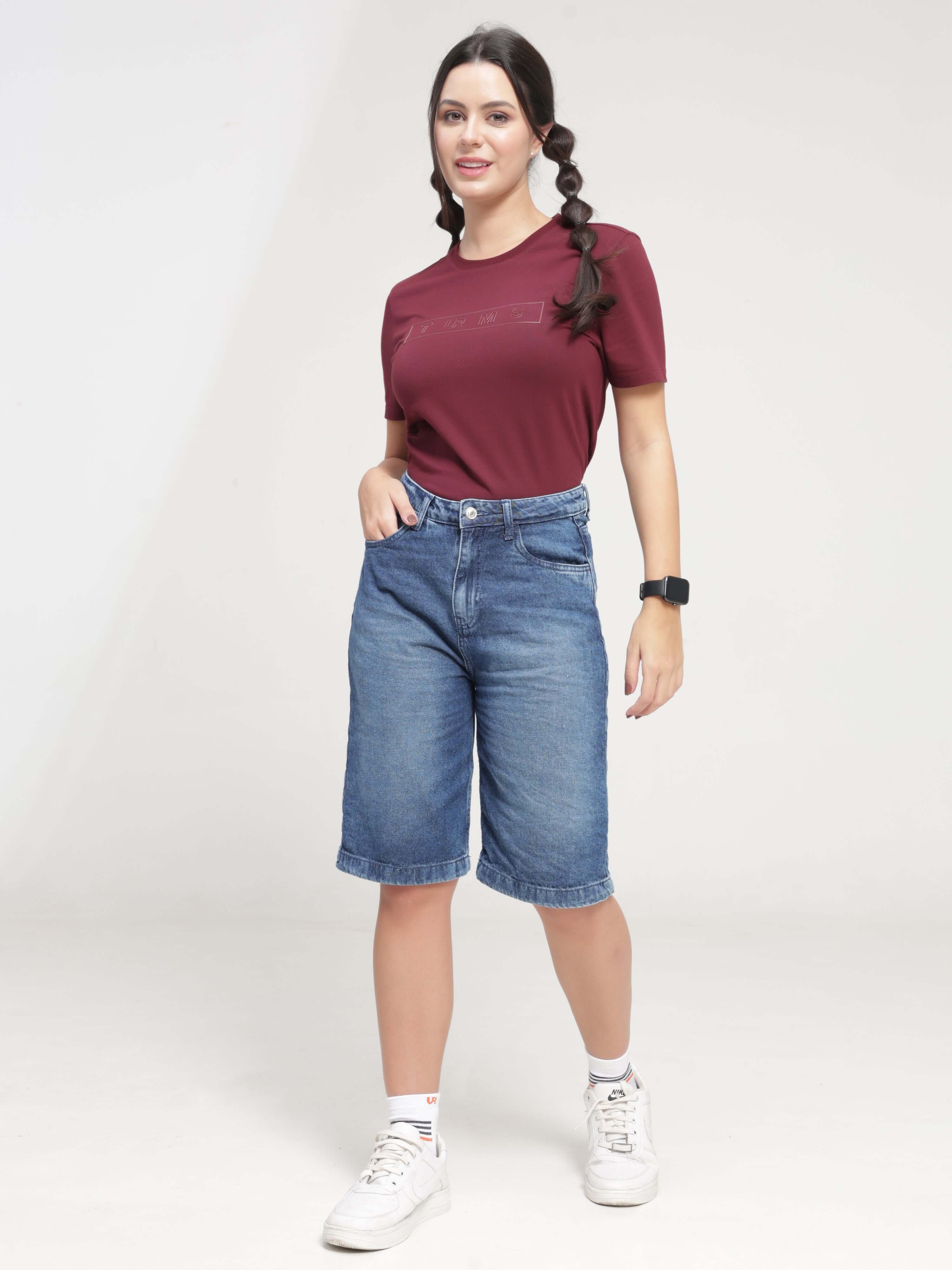 Woman wearing Burgundy Elite round-neck Turms T-shirt with tailored fit, stain-proof, anti-odor, and stretchable fabric, paired with denim shorts.