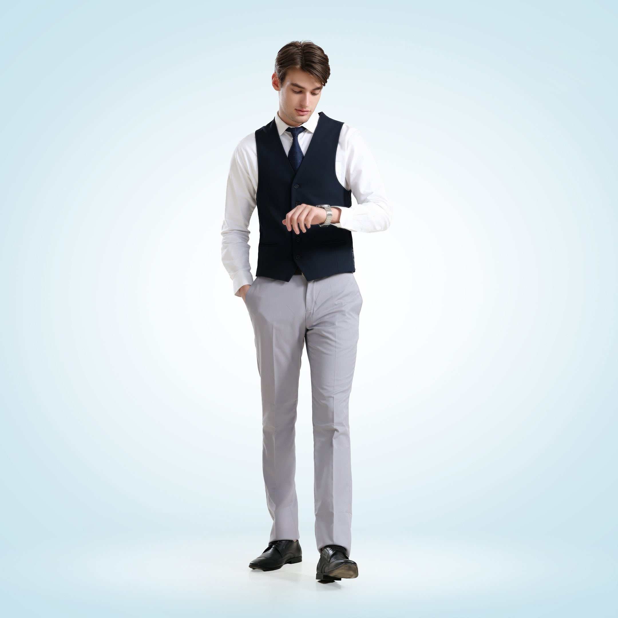 Man wearing a white Oxford Turms shirt with premium fixed bond collar and a navy vest, checking time on a watch.