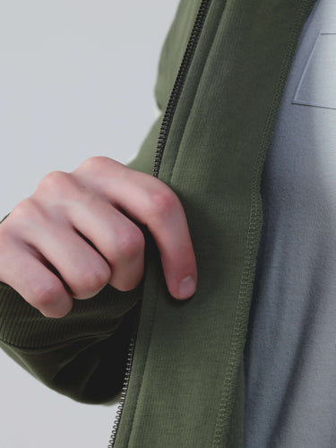 Close-up of a hand zipping up a green jacket from the Turms Intelligent Co-ord Set for men and women.