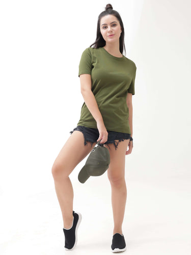Woman wearing a green round-neck Turms T-shirt, paired with black denim shorts and black sneakers, holding a matching green cap.