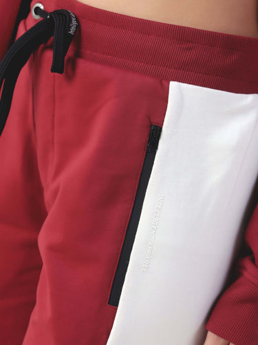 Close-up of stylish red joggers with white panel, featuring Turms anti-stain, waterproof, and anti-odour technology.