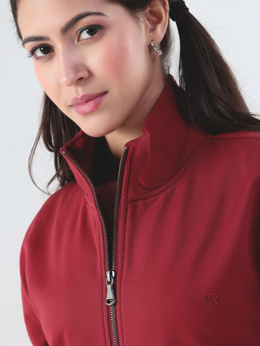 Close-up of a woman wearing a ruby red jacket with a brass zipper, showcasing modern design and style.