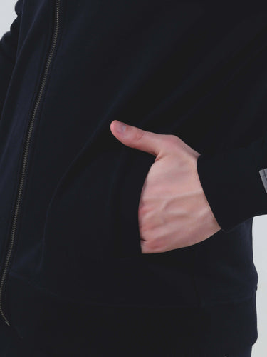 Close-up of a hand in the pocket of a black jacket, showcasing stylish, water-resistant fabric and sporty design.
