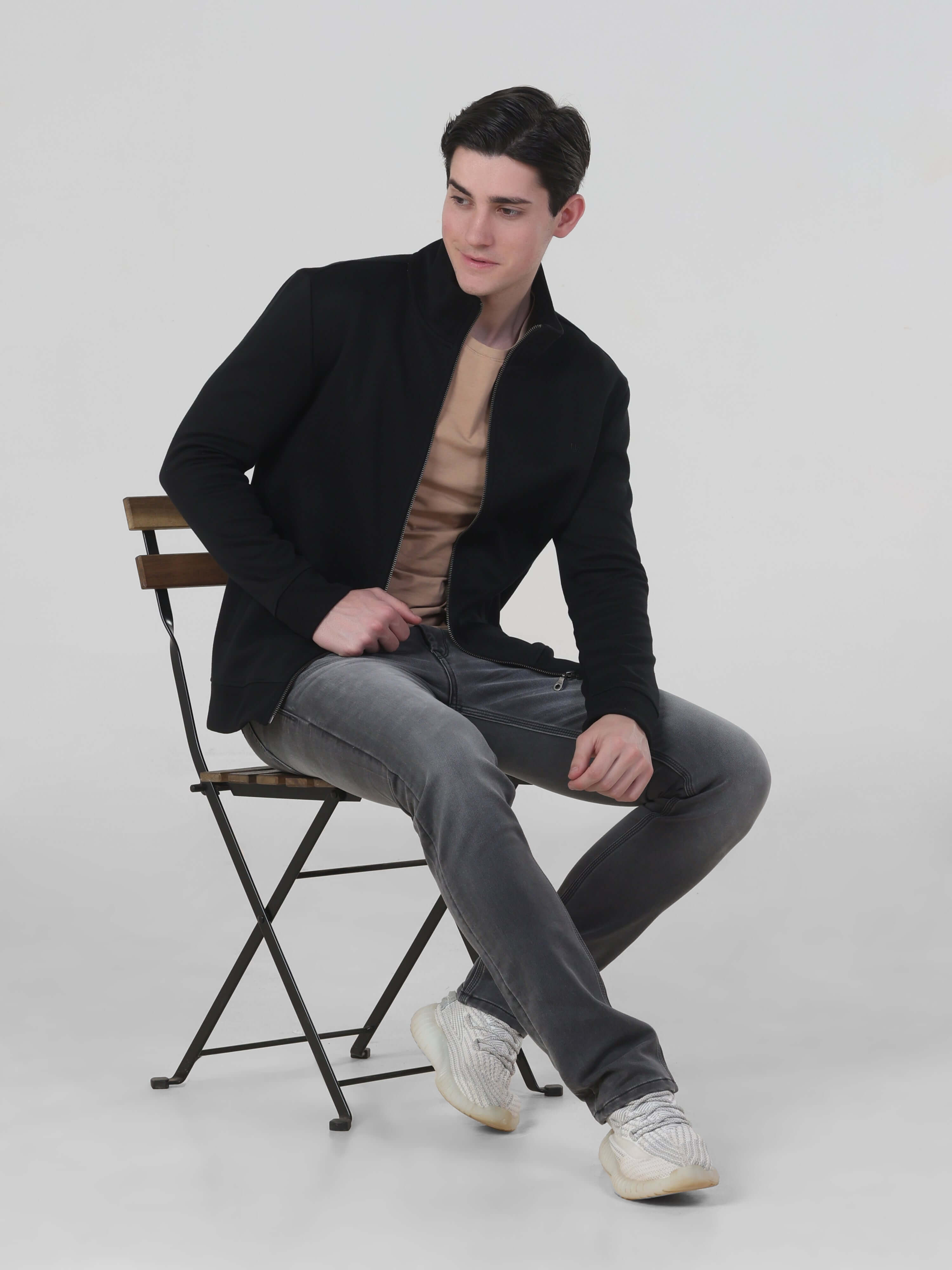 Man sitting on a chair wearing the Turms Intelligent Traveller Jacket, showcasing its style and comfort.