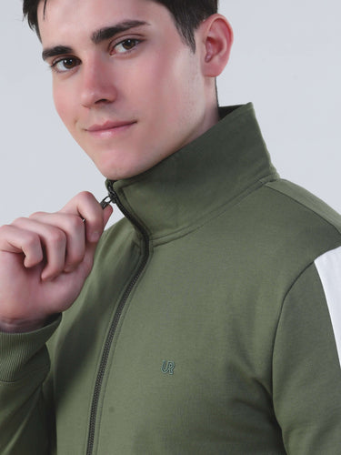 Model wearing a sleek green winter jacket with a high collar and brass zipper, showcasing style and comfort.