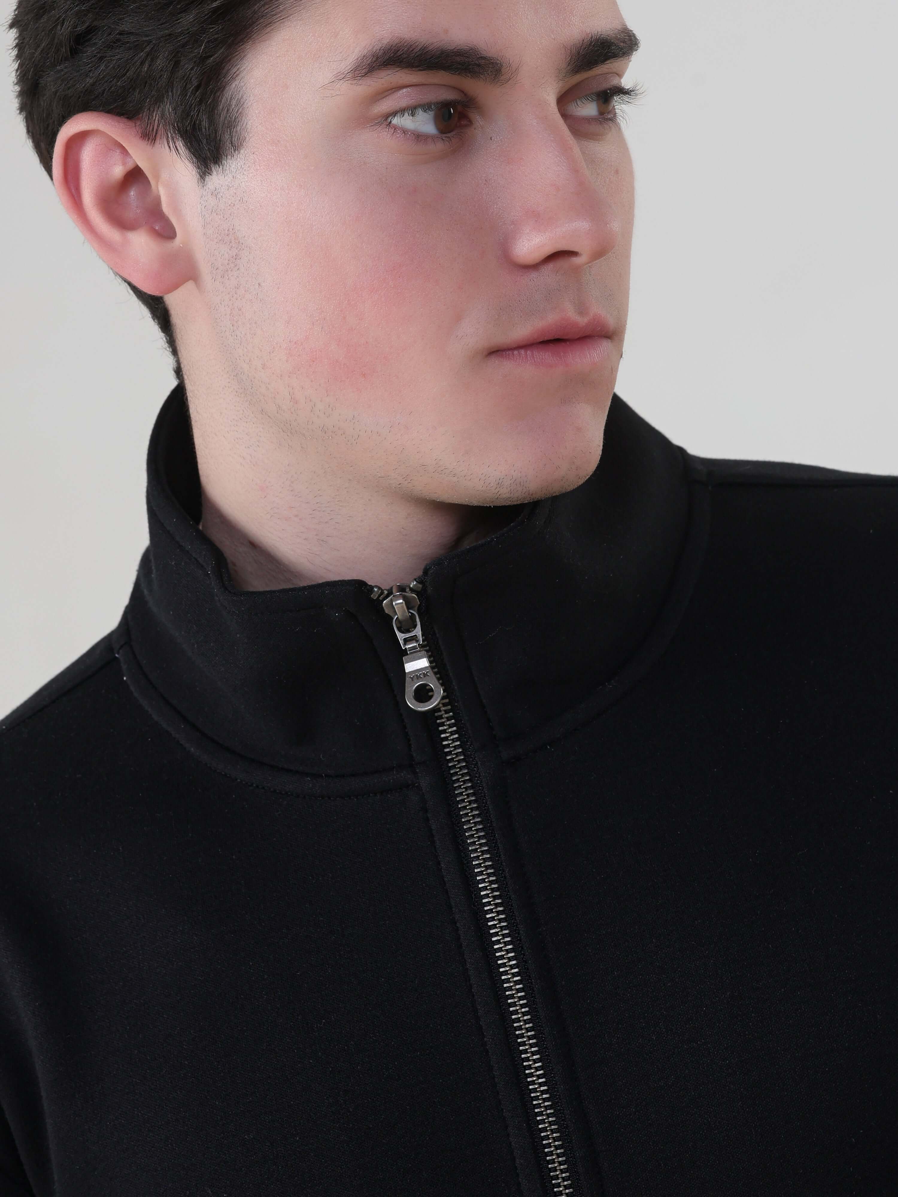 Close-up of a man wearing the Turms Intelligent Traveller Jacket, showcasing its sleek design and brass YKK zipper.