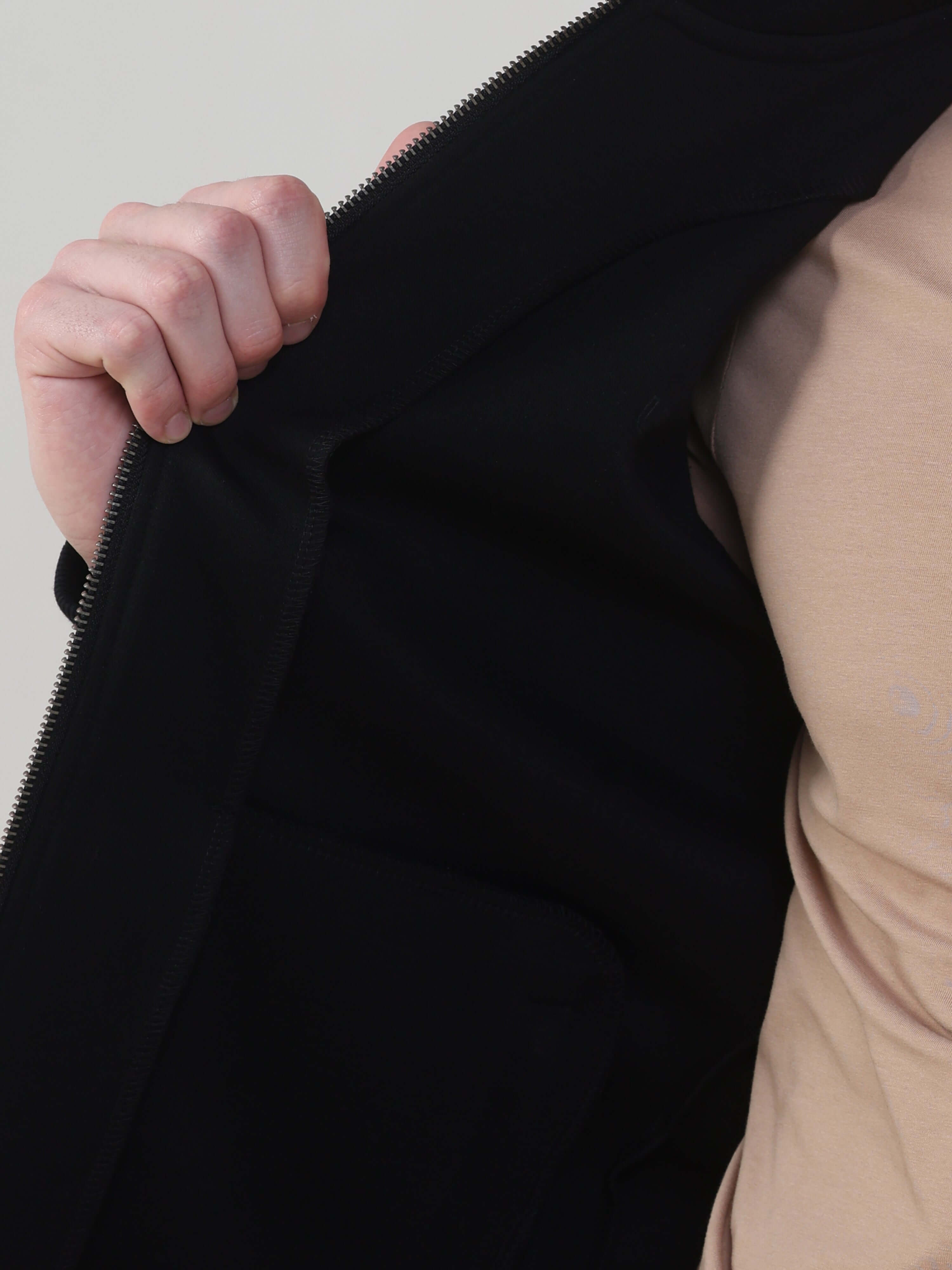 Close-up of a hand holding the zipper of the Turms Intelligent Traveller Jacket, showcasing its sleek lining and design.