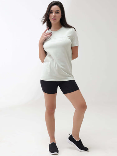 Woman wearing Lime Enigma Turms T-shirt with tailored fit and round neckline, showcasing anti-stain and anti-odor features, paired with black shorts.