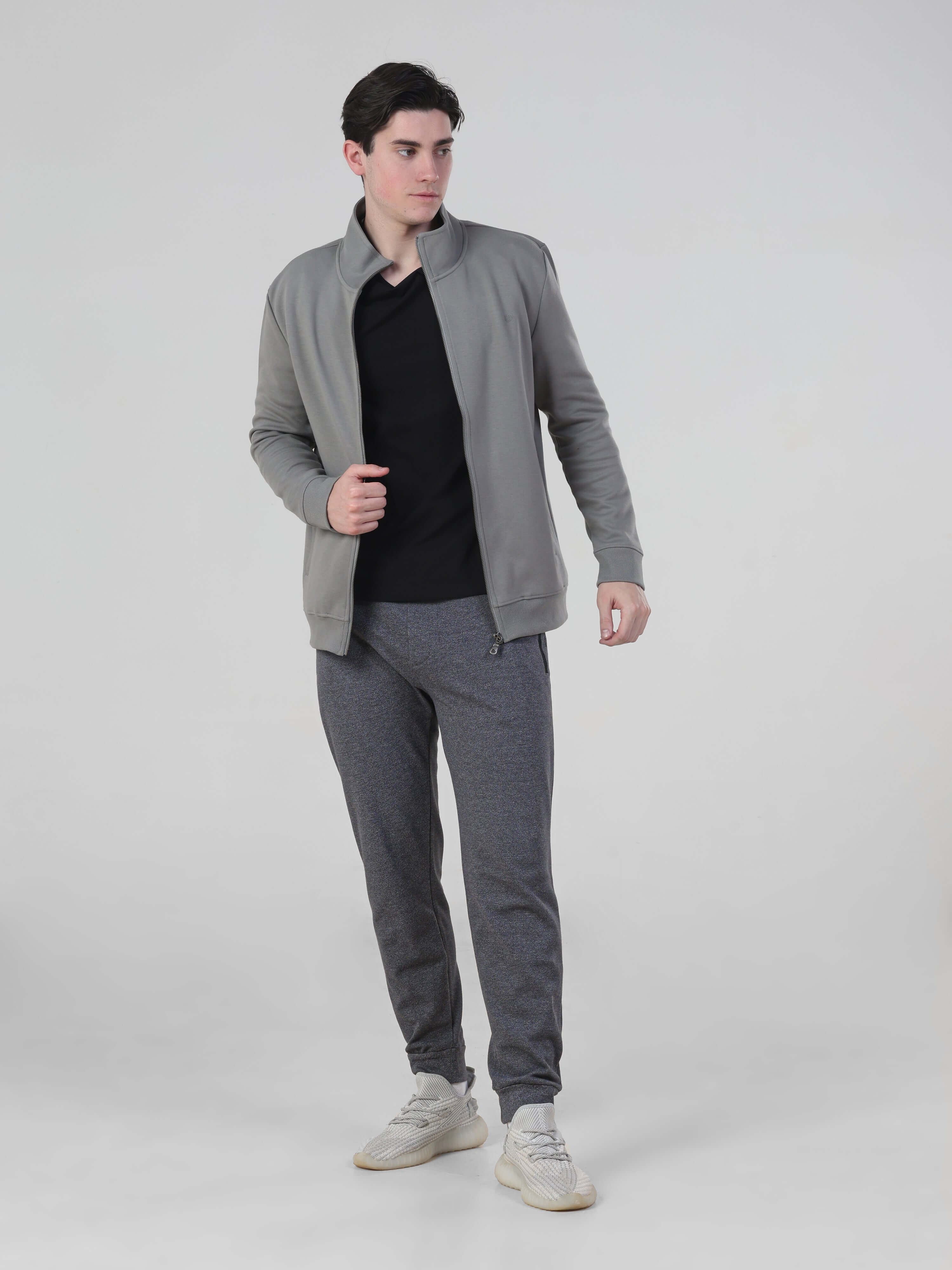 Man in charcoal joggers and grey jacket, showcasing men's stylish and comfortable travel outfit.