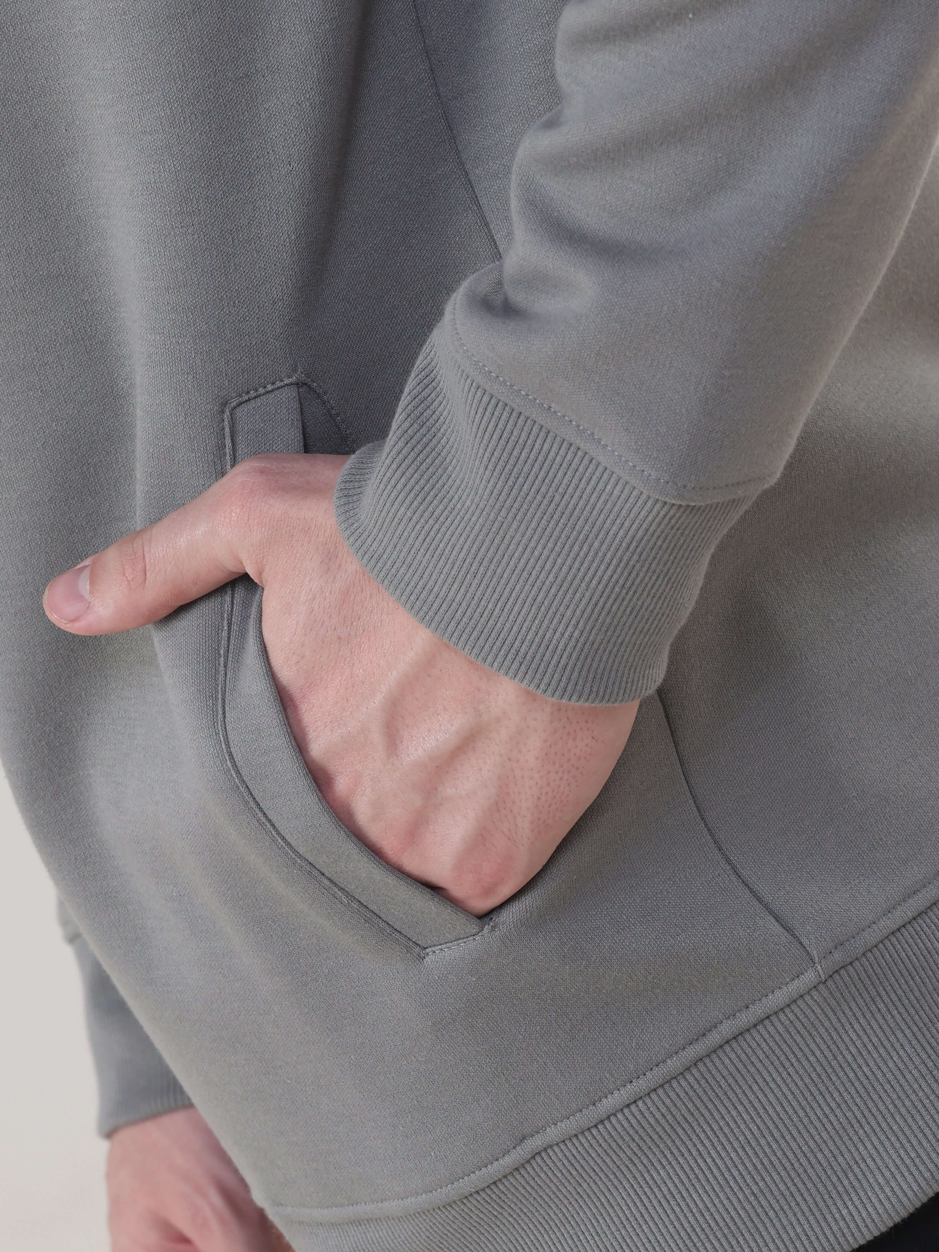 Close-up of a man's hand in the pocket of a grey Turms Intelligent Traveller Jacket, showcasing its comfort and style.