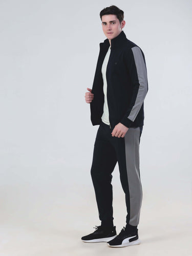 Man wearing Turms Intelligent co ord set in black and grey, featuring waterproof jackets and joggers.