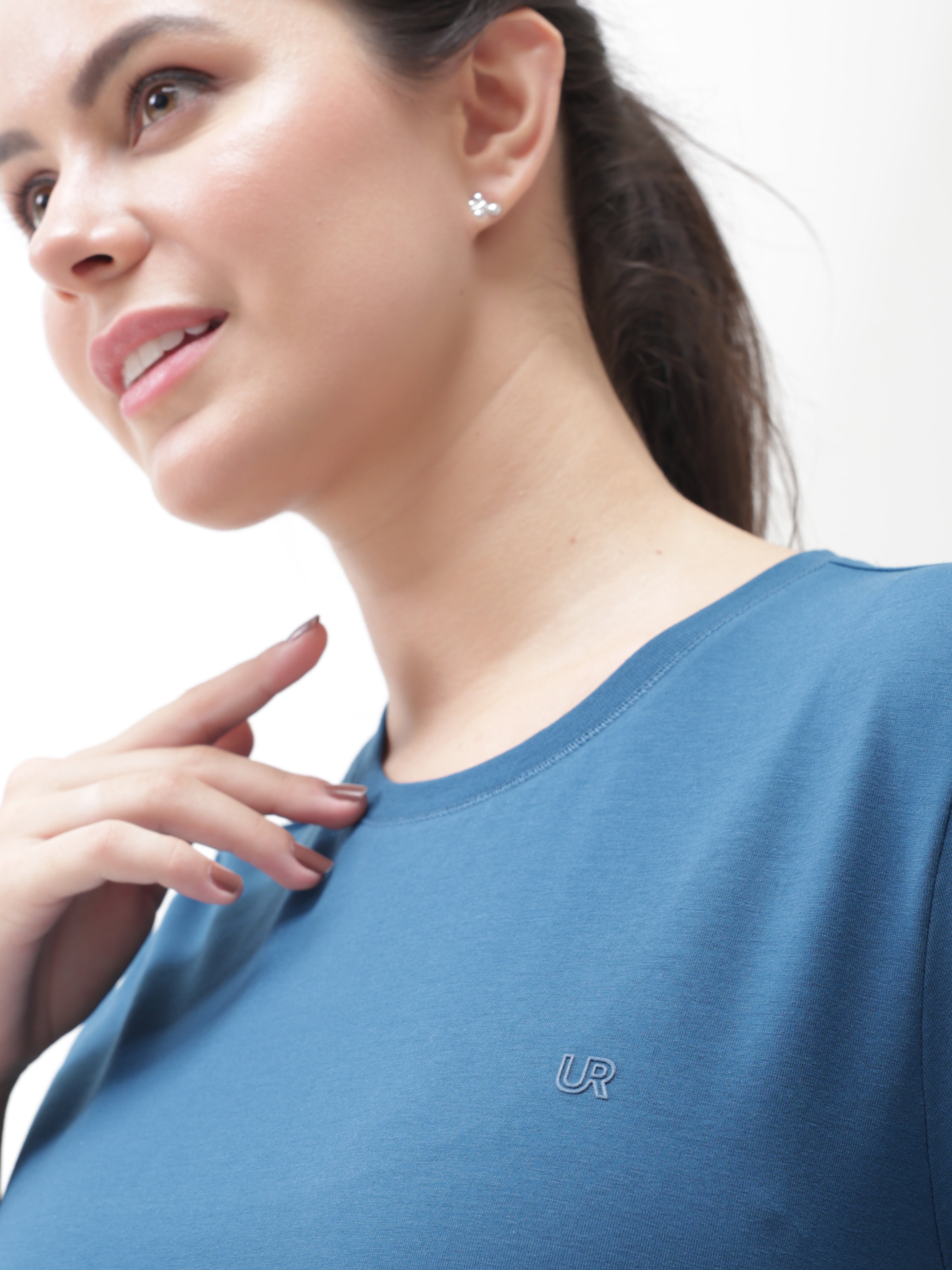 Woman wearing Sea Blue round-neck Turms T-shirt, showcasing anti-stain, anti-odour, and stretchable intelligent apparel with a tailored fit.